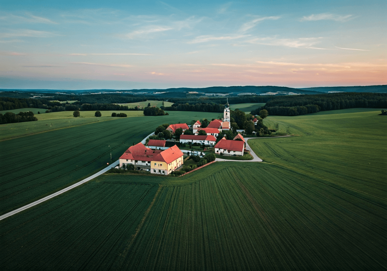 Aerial wide shot of the village of Dukovany in the Vysočina Region, rolling green landscape, clean rural architecture, editorial photography, soft natural light, 85mm lens, high resolution, no text, no letters