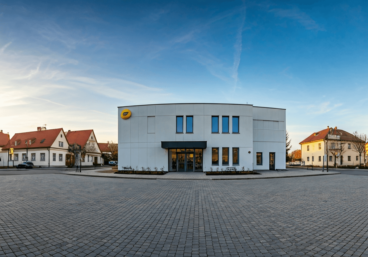 A wide-angle street view of a modern post office building in a quiet Czech village, clear signage, paved square, soft morning sunlight, editorial style, 85mm lens, high quality, no text, no letters