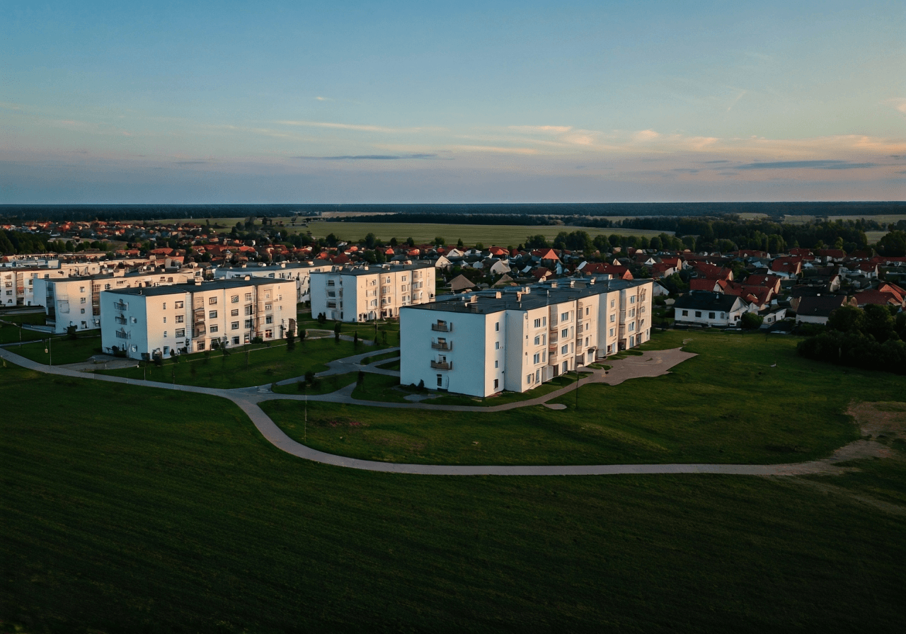 Aerial view of a clean, structured suburban residential area in Bánovce nad Bebravou with lush green surroundings, cinematic editorial photography, soft natural morning light, 85mm lens, high resolution, no text, no words, no letters