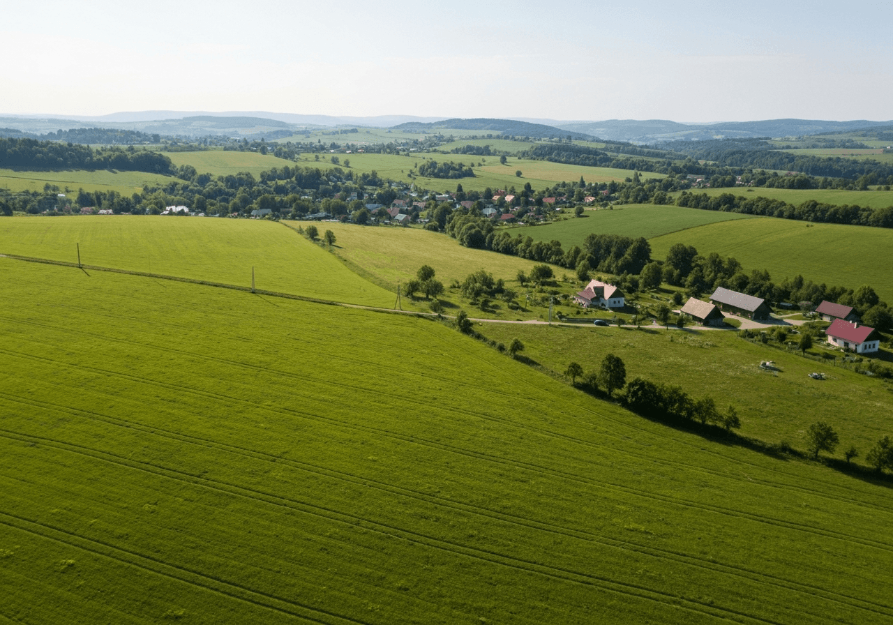 Aerial photography of the rolling hills and landscape near Vizovice, Zlínský kraj, lush green meadows and small village structures, serene atmosphere, natural sunlight, cinematic quality, 85mm lens, no text, no words, no letters
