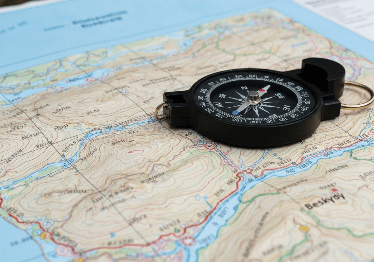 A professional hiking compass resting on a detailed topographical map of the Beskydy mountains, soft natural light, editorial photography, 85mm lens, sharp focus on coordinates, clean aesthetic, no text, no words, no letters.